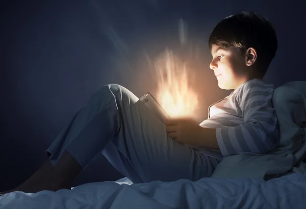 Мальчик с планшетным компьютером в кровати — стоковое фото