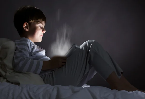 Niño usando tableta pc en la cama —  Fotos de Stock