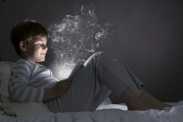 Boy using tablet pc in bed — Stock Photo, Image