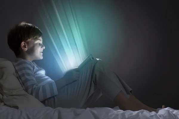 Boy using tablet pc in bed — Stock Photo, Image