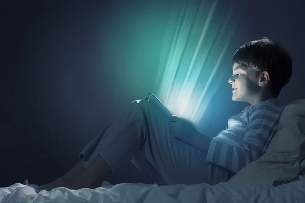 Boy using tablet pc in bed — Stock Photo, Image