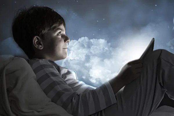 Boy using tablet pc in bed — Stock Photo, Image