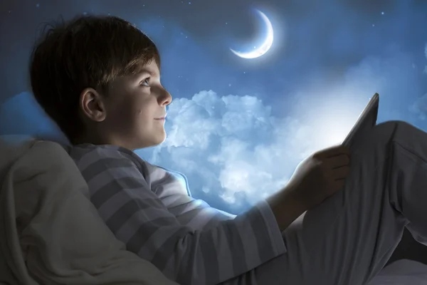 Pojke med hjälp av TabletPC i sängen — Stockfoto