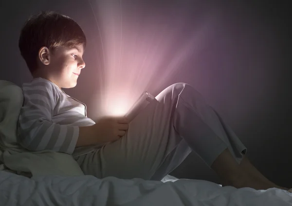 Boy using tablet pc in bed — Stock Photo, Image