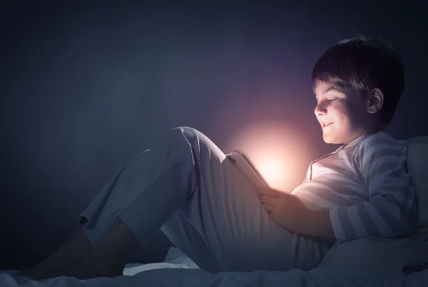 Boy použití počítače tablet pc v posteli — Stock fotografie