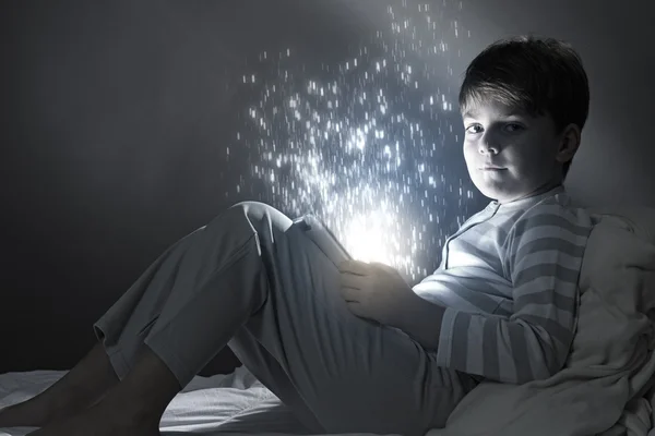 Мальчик с планшетным компьютером в кровати — стоковое фото