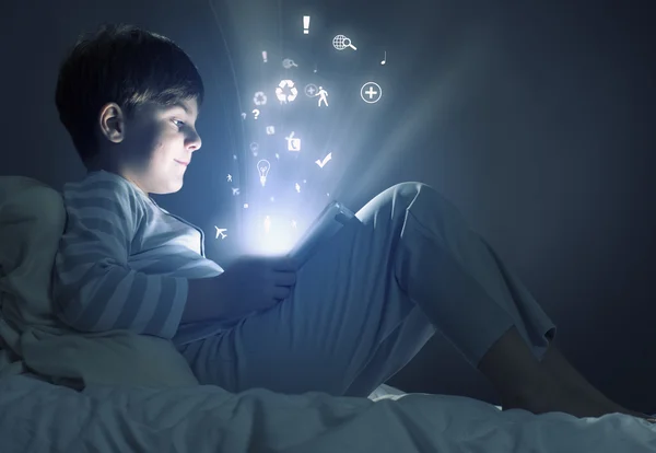 Boy using tablet pc in bed — Stock Photo, Image