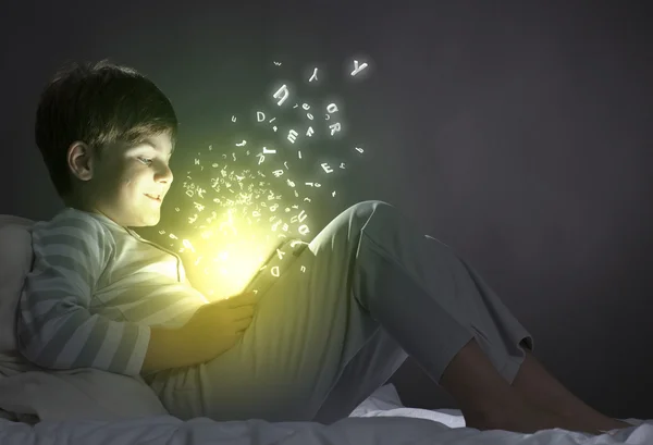 Boy using tablet pc in bed — Stock Photo, Image