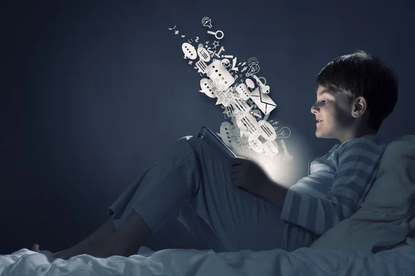 Boy using tablet pc in bed — Stock Photo, Image