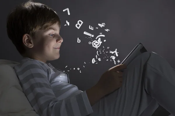 Boy using tablet pc in bed — Stock Photo, Image