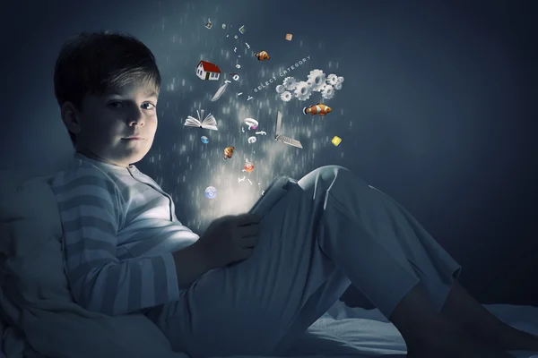 Boy using tablet pc in bed — Stock Photo, Image