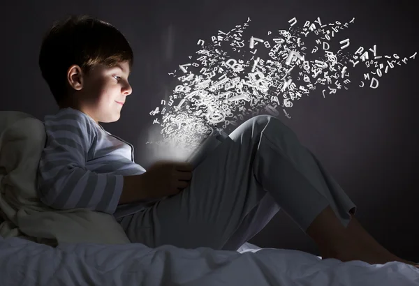 Boy using tablet pc in bed — Stock Photo, Image