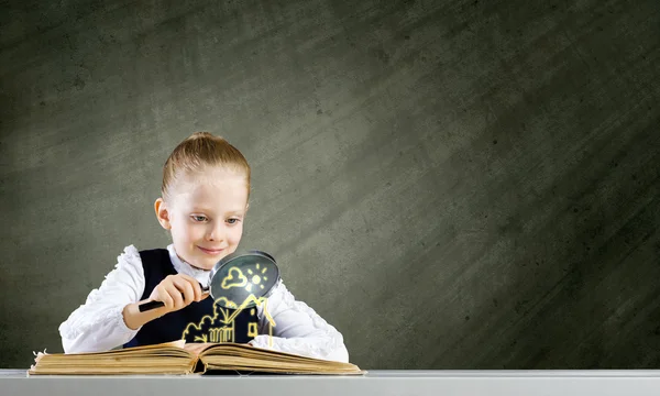 Schoolmeisje onderzoeken geopend boek — Stockfoto