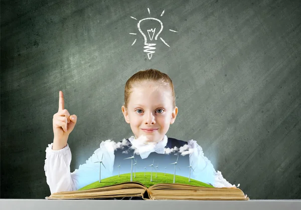 Schoolgirl looking in book with windmills — Stock Photo, Image