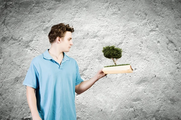 Man håller boken med gröna träd — Stockfoto