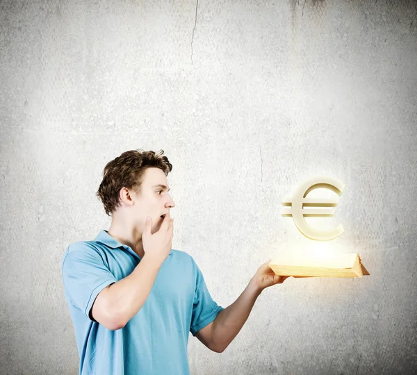 Homem segurando livro com sinal de euro — Fotografia de Stock