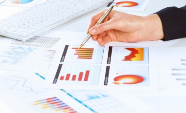 eli kalem tutan ve grafikler işaret ediyor