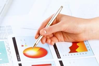 eli kalem tutan ve grafikler işaret ediyor