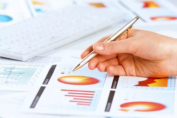 Hand holding pen and pointing at graphs — Stock Photo, Image