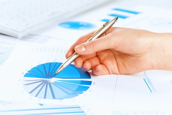 Hand holding pen and pointing at graphs — Stock Photo, Image