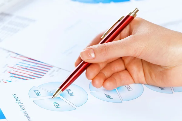 Hand holding pen and pointing at graphs — Stock Photo, Image