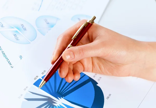 Hand holding pen en wijzend op de grafieken — Stockfoto