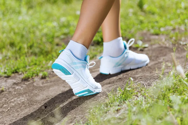 Pieds féminins courant sur la route — Photo