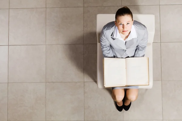 Businesswoman livro de leitura na cadeira — Fotografia de Stock