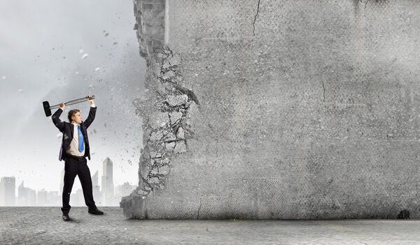 Businessman breaking cement wall
