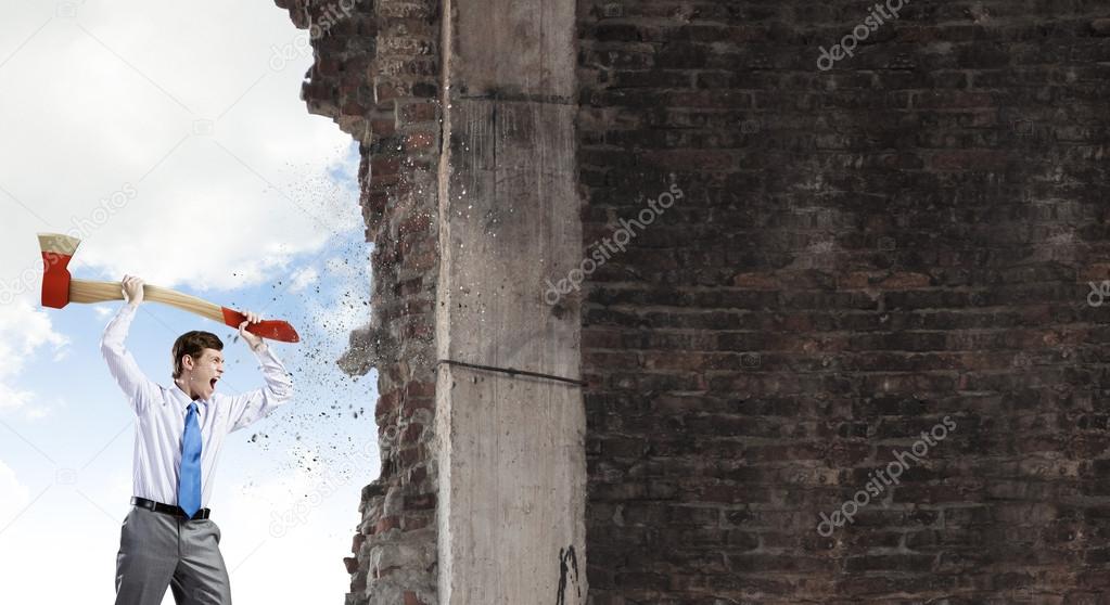 Businessman breaking cement wall