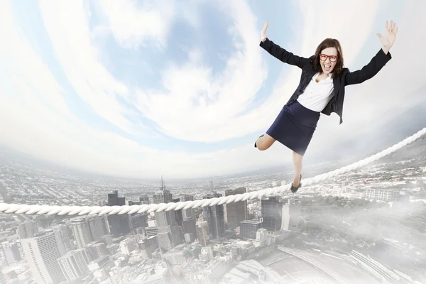 Risky businesswoman balancing on rope — Stock Photo, Image