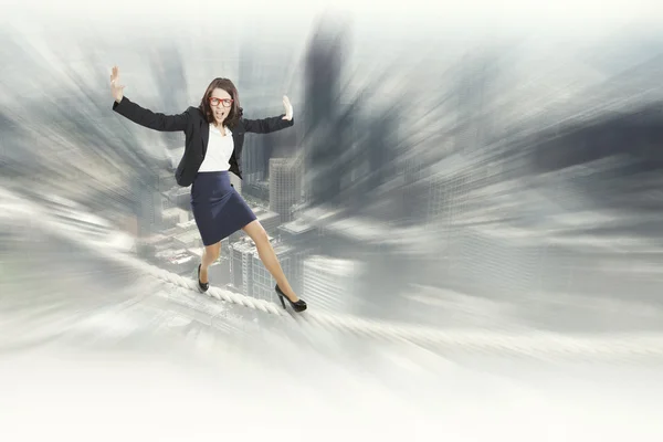 Risky businesswoman balancing on rope — Stock Photo, Image