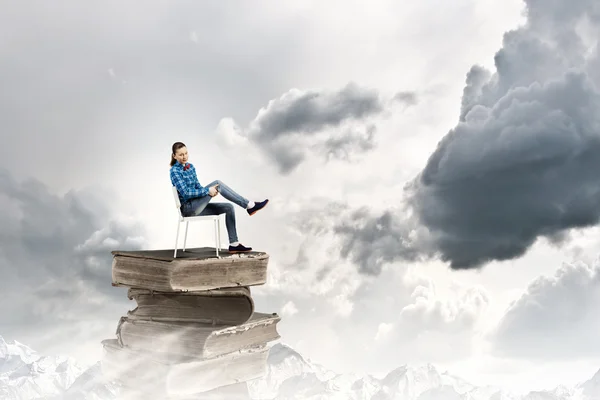 Girl sitting on pile of books — Stock Photo, Image