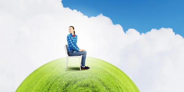 Woman sitting in chair on green planet — Stock Photo, Image