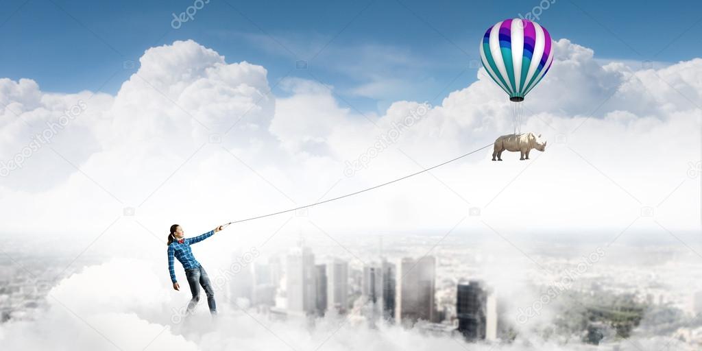 Woman and rhino flying in sky