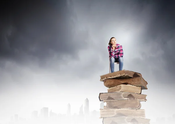 Fille assise sur des livres — Photo