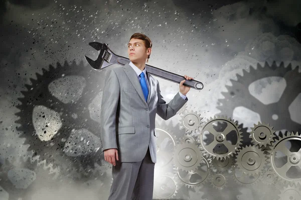 Businessman with wrench and cogwheels — Stock Photo, Image