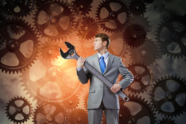 Businessman with wrench and cogwheels — Stock Photo, Image