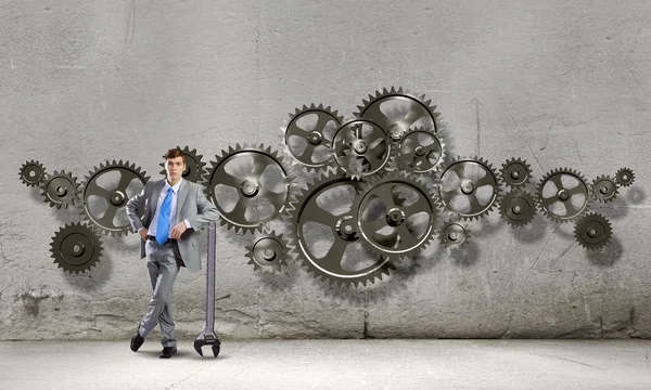 Businessman leaning wrench and cogwheel — Stock Photo, Image