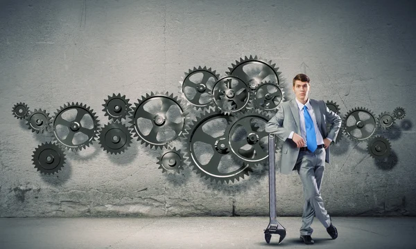 Businessman leaning wrench and cogwheel — Stock Photo, Image