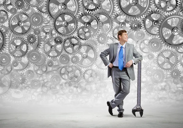 Businessman leaning wrench and cogwheel — Stock Photo, Image