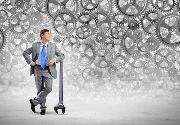 Businessman leaning wrench and cogwheel — Stock Photo, Image