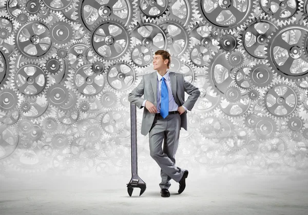 Businessman leaning wrench and cogwheel — Stock Photo, Image