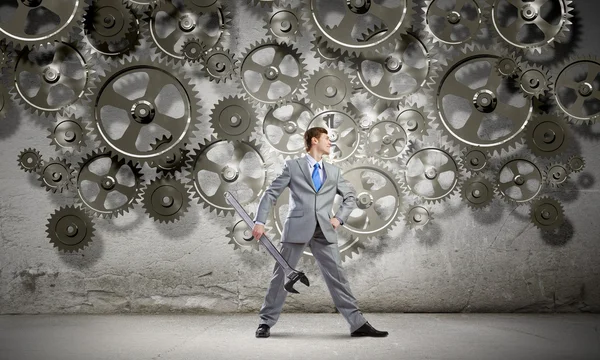 Businessman with wrench and cogwheels — Stock Photo, Image