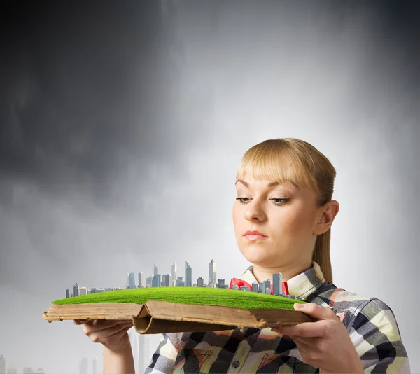 Mujer sosteniendo libro con modelo de ciudad — Foto de Stock