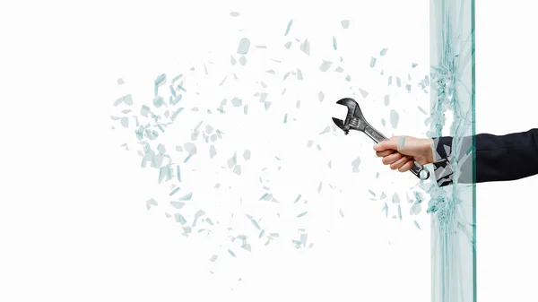 Hand breaking glass with wrench — Stock Photo, Image