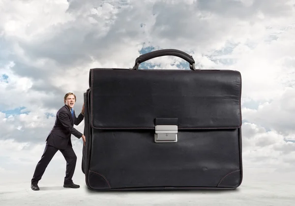 Businessman pushing big heavy suitcase — Stock Photo, Image