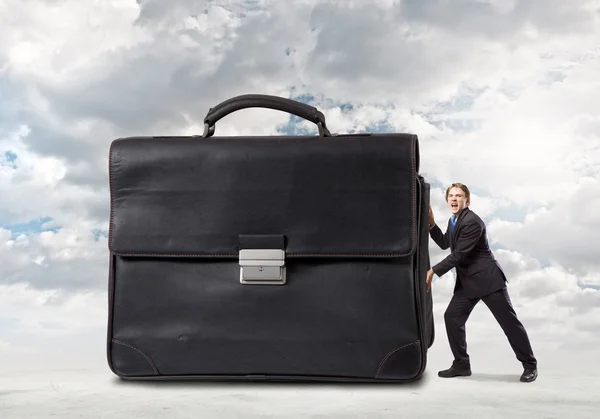 Бизнесмен толкает большой тяжелый чемодан — стоковое фото