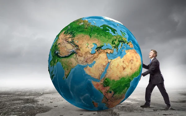 Businessman pushing big Earth planet — Stock Photo, Image