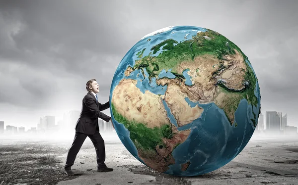 Businessman pushing big Earth planet — Stock Photo, Image